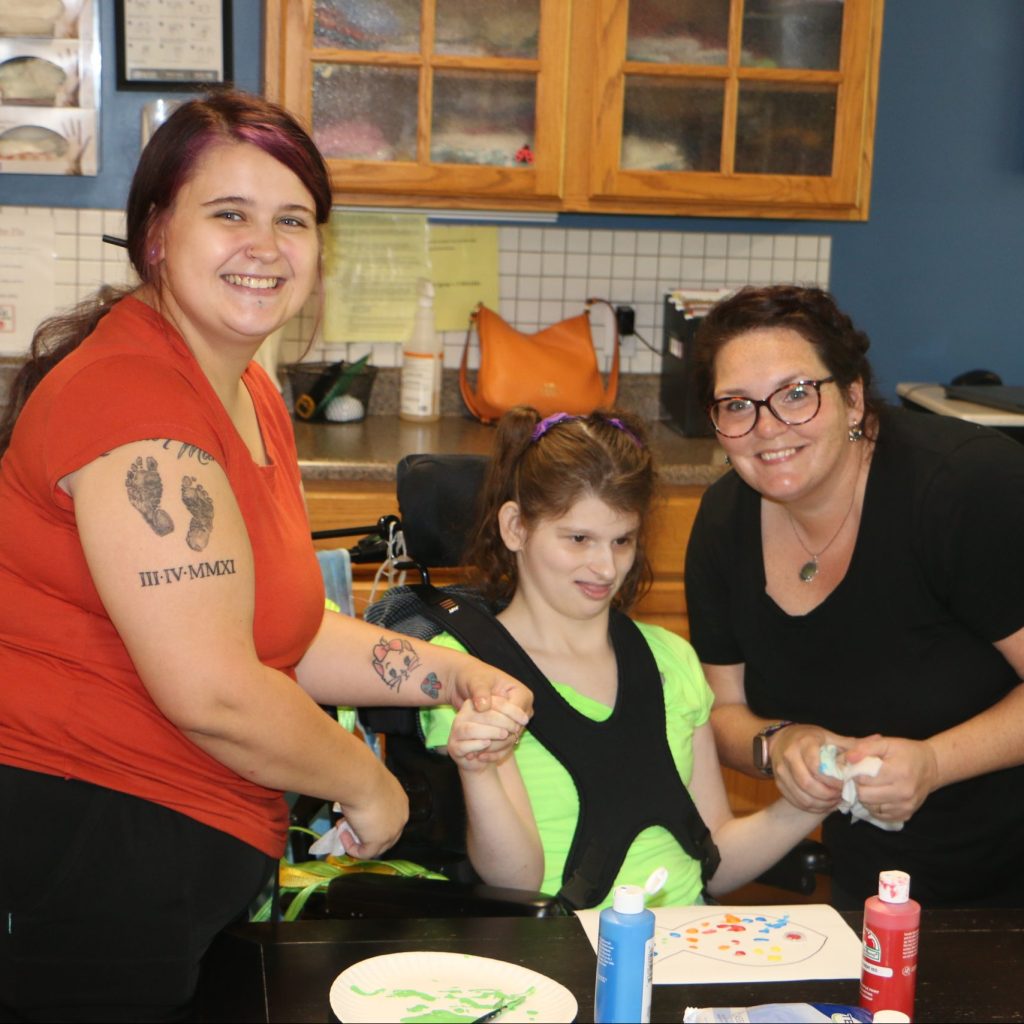 Staff members helping patient at Pony Bird do paint and craft.